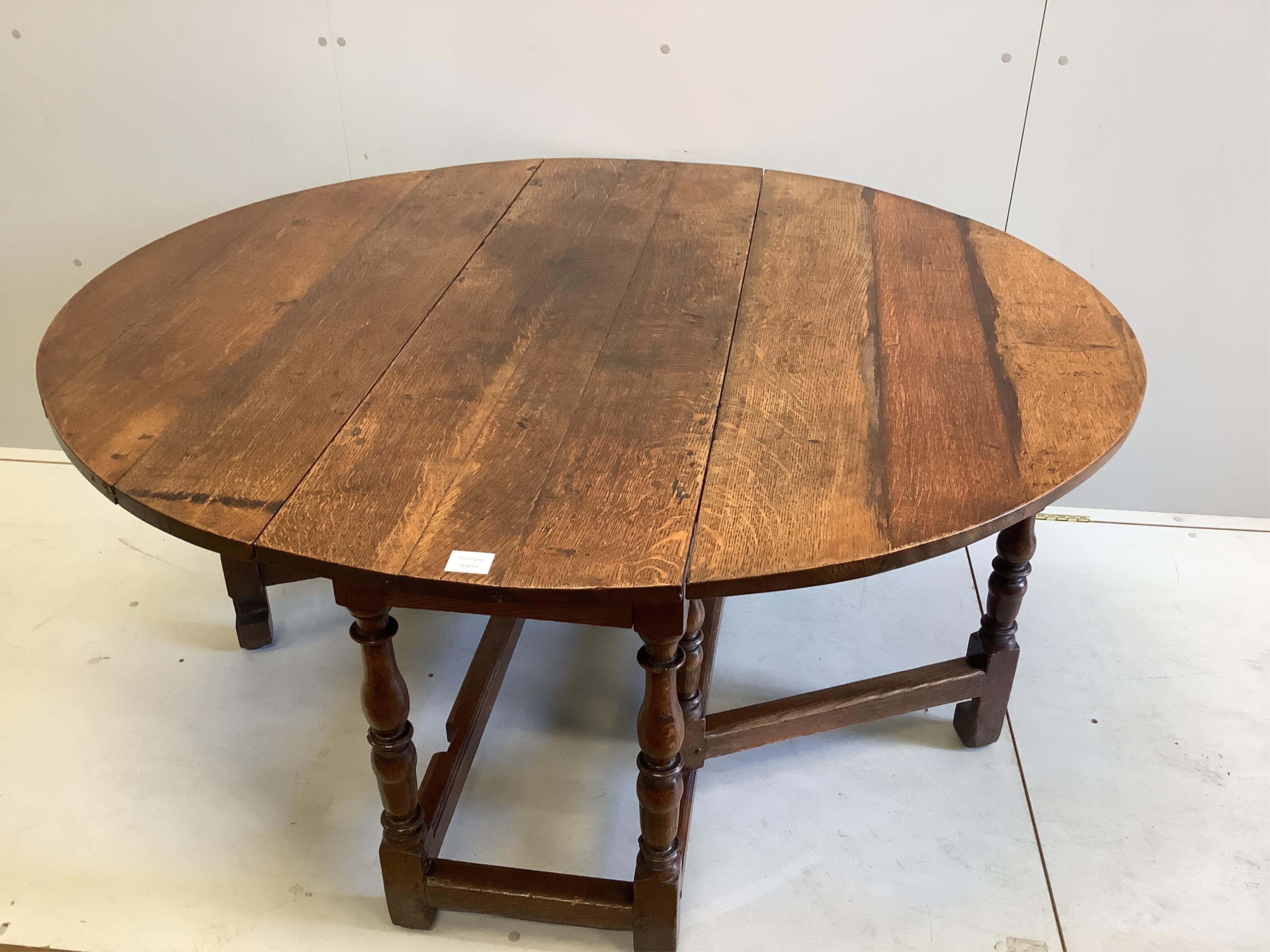 An 18th century oval oak gateleg dining table, width 139cm extended, depth 127cm, height 70cm. Condition - good